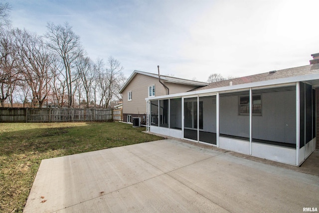 rear view of property featuring a patio, a lawn, a sunroom, central AC, and a fenced backyard