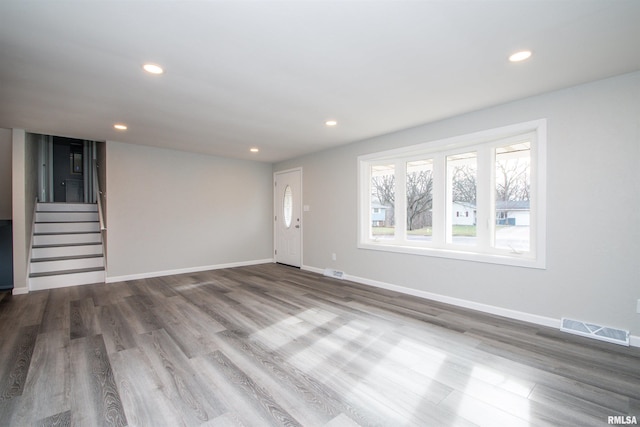 unfurnished living room featuring baseboards, visible vents, wood finished floors, stairs, and recessed lighting