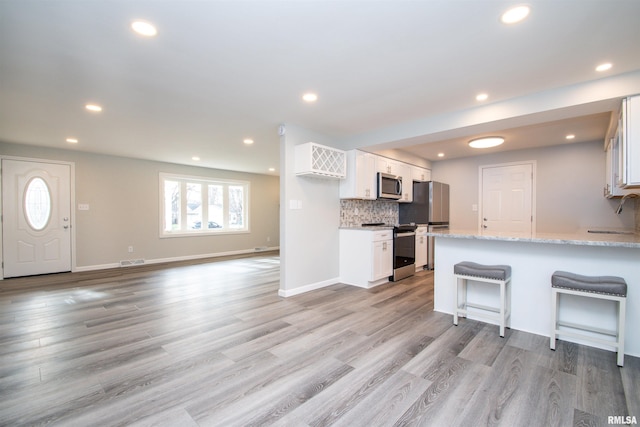 kitchen featuring stainless steel appliances, white cabinetry, a sink, and light stone counters