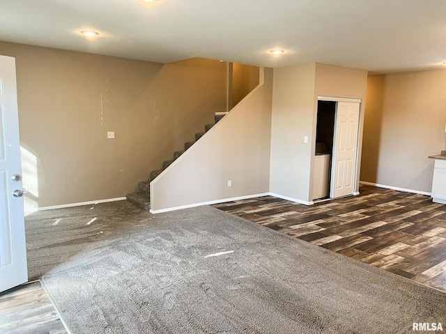 unfurnished living room with stairway, wood finished floors, and baseboards