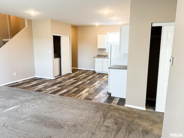 kitchen featuring baseboards, dark carpet, white cabinets, and dark wood-style flooring