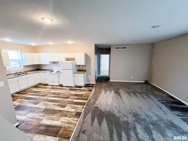 kitchen with visible vents, white cabinetry, a sink, white appliances, and baseboards