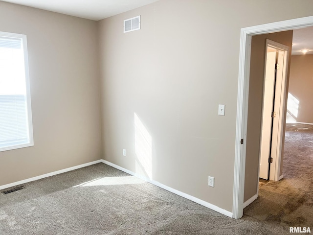 carpeted spare room featuring visible vents and baseboards