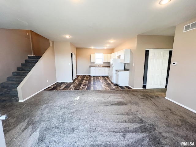 unfurnished living room featuring baseboards, stairs, visible vents, and dark colored carpet