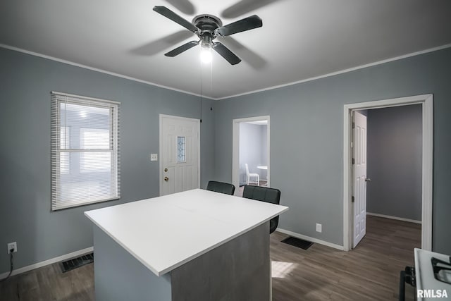 kitchen featuring light countertops, visible vents, ornamental molding, a kitchen island, and baseboards