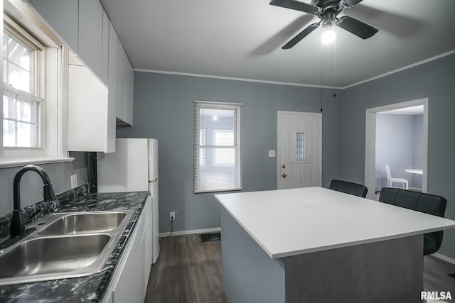 kitchen featuring dark wood-style flooring, a sink, white cabinetry, a kitchen breakfast bar, and dark countertops