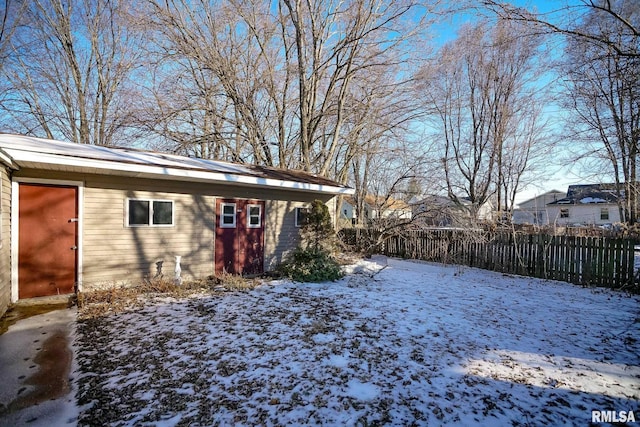 snowy yard featuring fence and an outbuilding