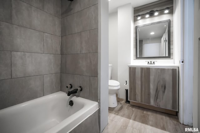 bathroom with toilet, shower / washtub combination, wood finished floors, and vanity