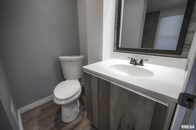 bathroom featuring baseboards, vanity, toilet, and wood finished floors