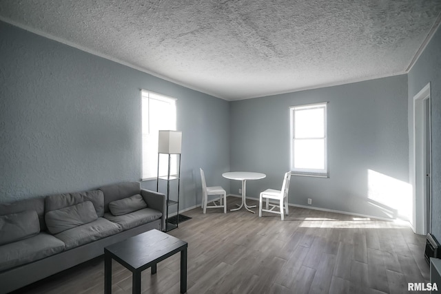 unfurnished living room with a textured ceiling, baseboards, wood finished floors, and a textured wall