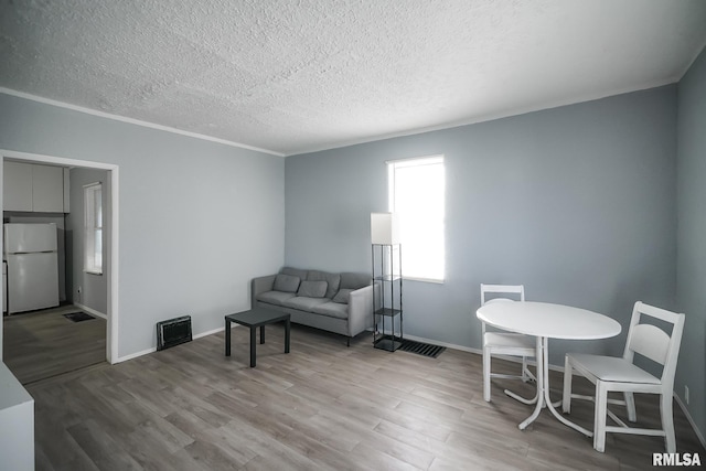 living area with visible vents, a textured ceiling, and wood finished floors