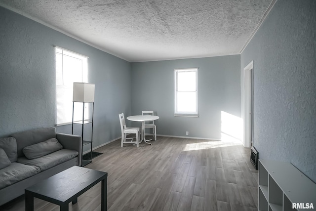 living room with visible vents, a textured wall, a textured ceiling, wood finished floors, and baseboards