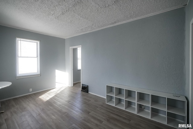 empty room featuring a textured ceiling, a textured wall, wood finished floors, and baseboards