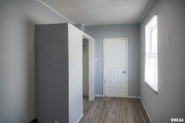 corridor with light wood-style floors and baseboards