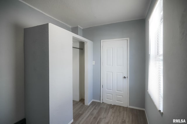 unfurnished bedroom with a closet, light wood-type flooring, and baseboards