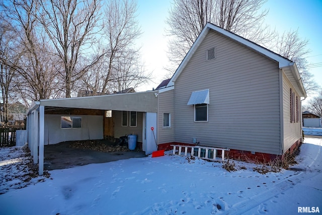 snow covered rear of property with a carport