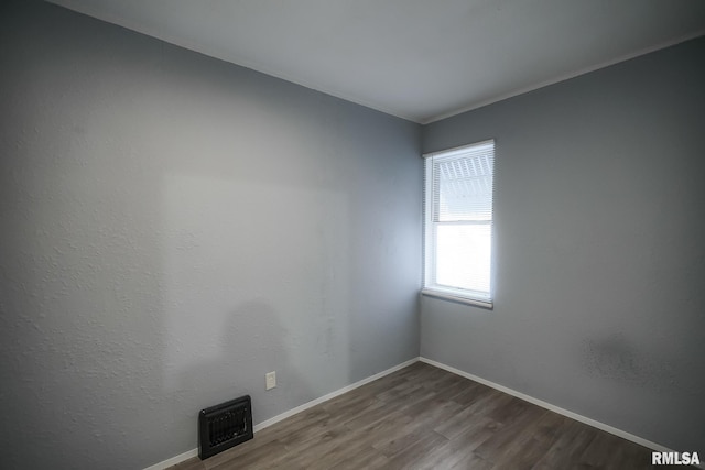 unfurnished room featuring visible vents, baseboards, and wood finished floors