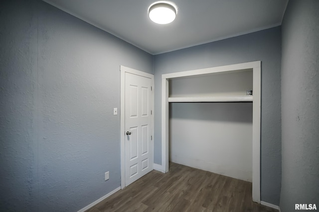 unfurnished bedroom featuring a closet and dark wood-style flooring