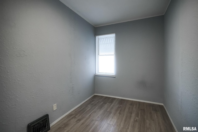 spare room with baseboards, visible vents, and wood finished floors