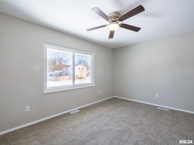 carpeted spare room with baseboards, visible vents, and ceiling fan