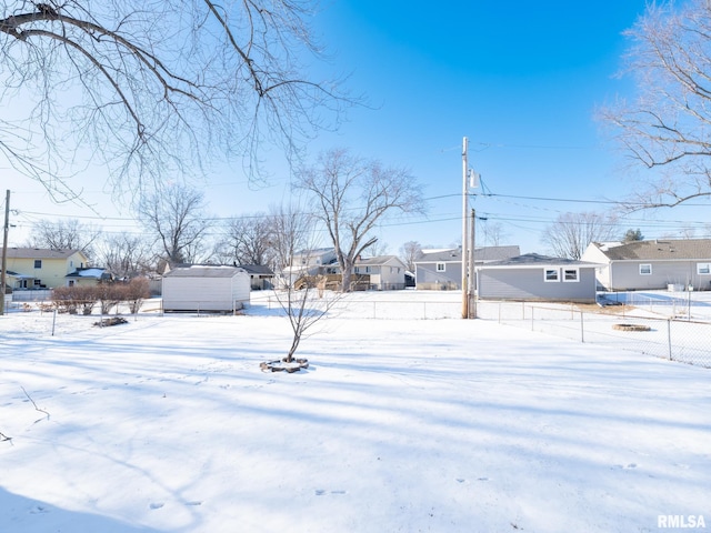 yard covered in snow with a residential view and fence