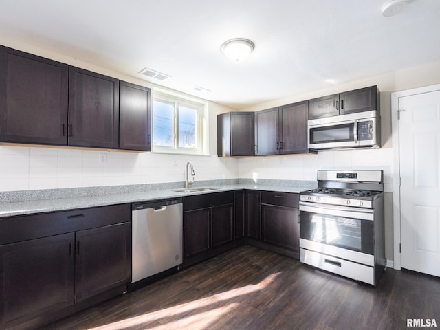 kitchen with tasteful backsplash, visible vents, appliances with stainless steel finishes, dark brown cabinets, and a sink