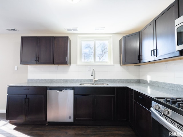 kitchen with dark brown cabinets, appliances with stainless steel finishes, a sink, and visible vents