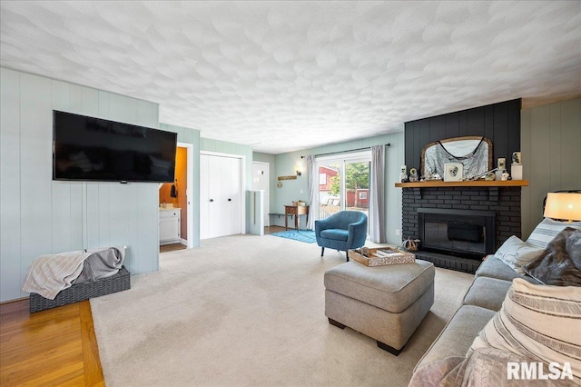 living area with a textured ceiling, a fireplace, and light carpet