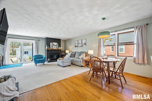 dining area with a textured ceiling, a fireplace, visible vents, and hardwood / wood-style floors