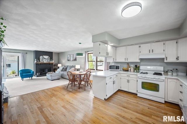 kitchen featuring open floor plan, light countertops, white gas range oven, and white cabinetry