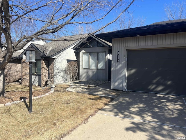 view of front of house featuring a garage, concrete driveway, and a shingled roof