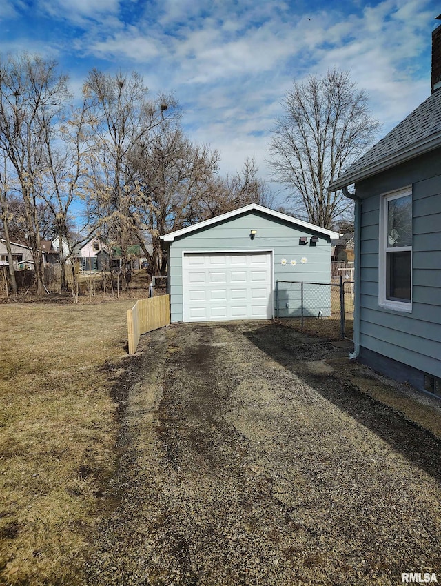 detached garage featuring driveway and fence