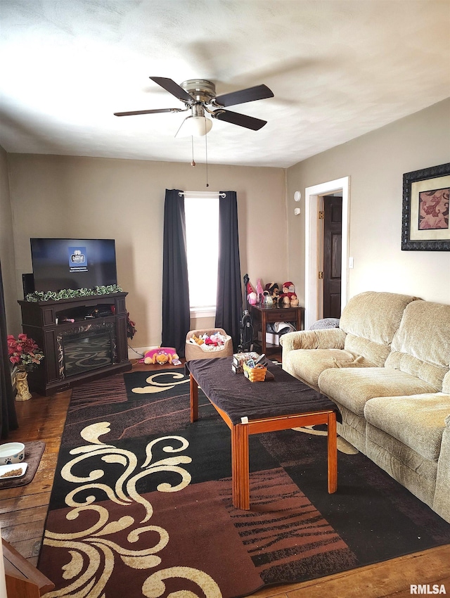 living area featuring a ceiling fan, dark wood-style flooring, and a fireplace