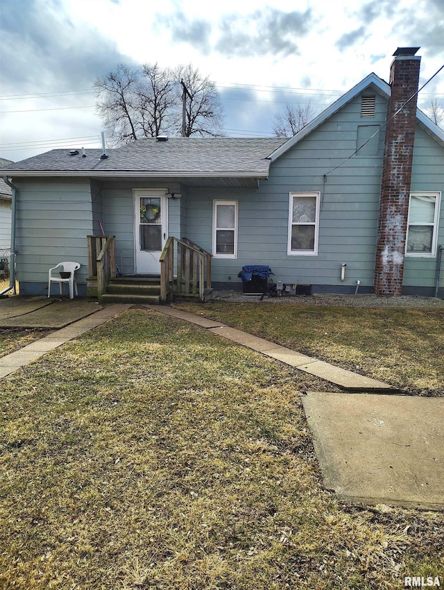 view of front of house with a shingled roof and a front lawn