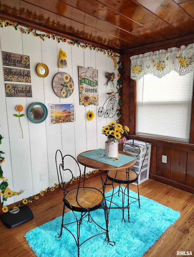 dining room with wood walls, wood ceiling, and wood finished floors