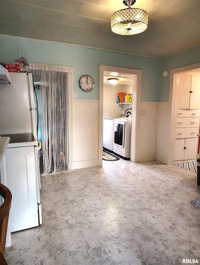 interior space featuring a wainscoted wall, washer / clothes dryer, white appliances, and wood walls