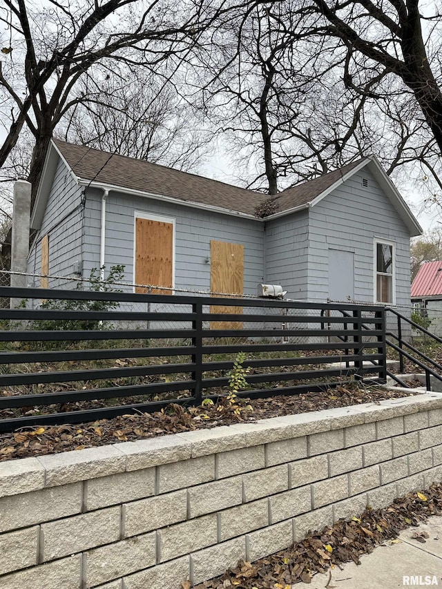 view of front of house with a fenced front yard and a shingled roof