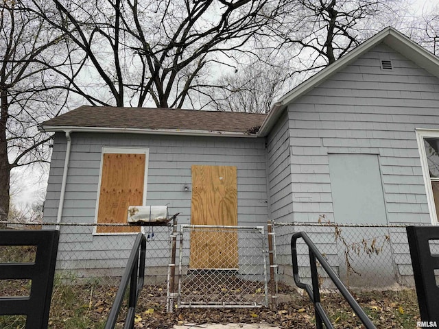 view of property exterior featuring a fenced front yard and a shingled roof