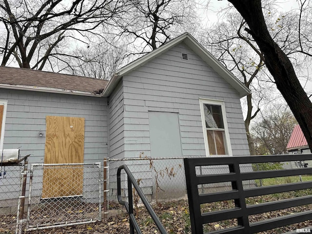 back of house with a fenced front yard and roof with shingles