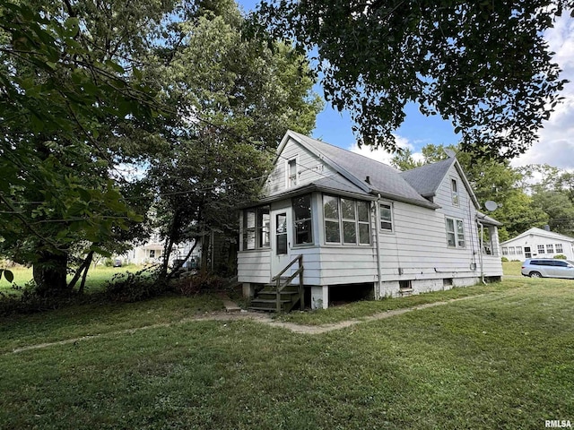 view of side of property featuring entry steps, roof with shingles, and a yard