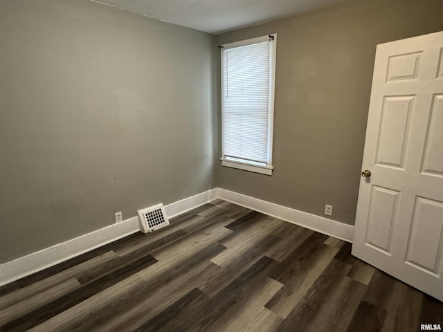 spare room featuring dark wood-style floors, visible vents, and baseboards