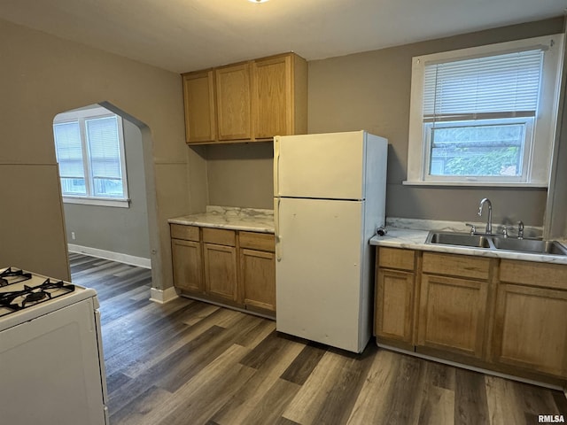 kitchen with white appliances, arched walkways, a sink, light countertops, and a wealth of natural light