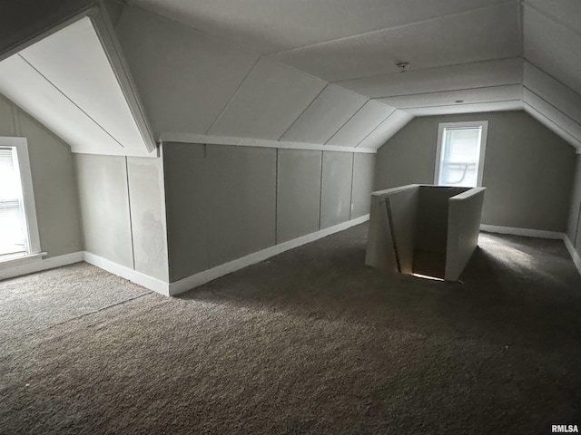 bonus room with lofted ceiling and dark carpet