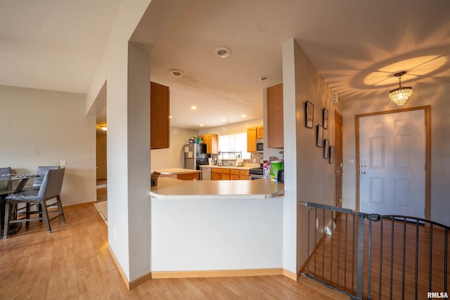 kitchen featuring stainless steel appliances, recessed lighting, light countertops, light wood-style flooring, and baseboards