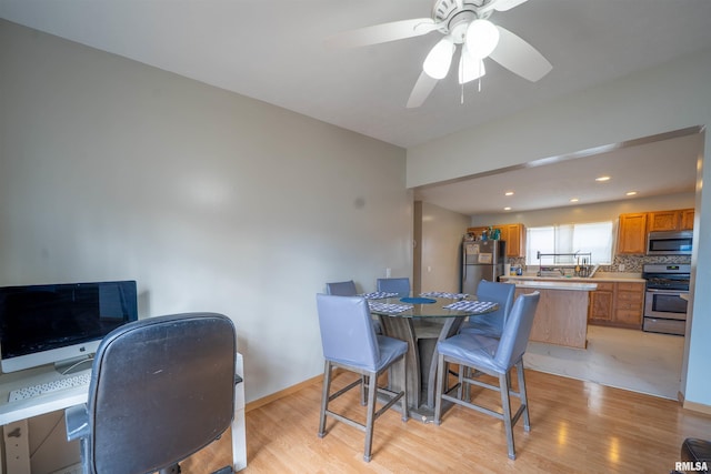 dining space featuring a ceiling fan, baseboards, and light wood finished floors