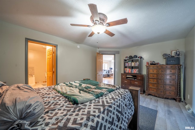 bedroom with a textured ceiling, connected bathroom, a ceiling fan, and light wood-style floors