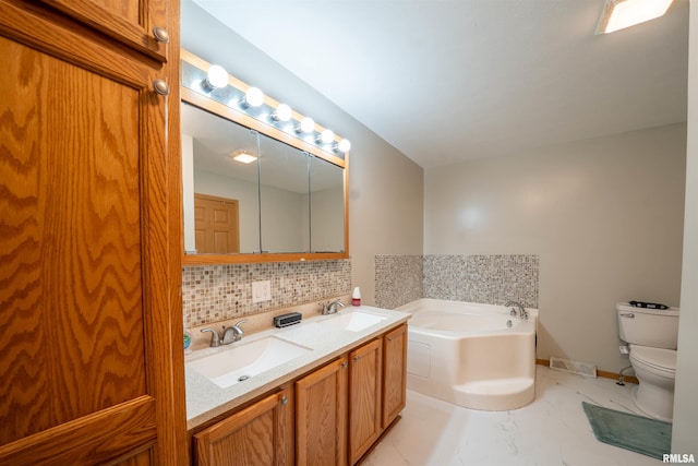 bathroom with decorative backsplash, a sink, toilet, and a bath