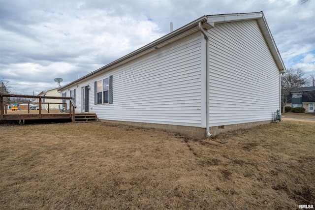 view of side of home featuring crawl space, a deck, and a yard