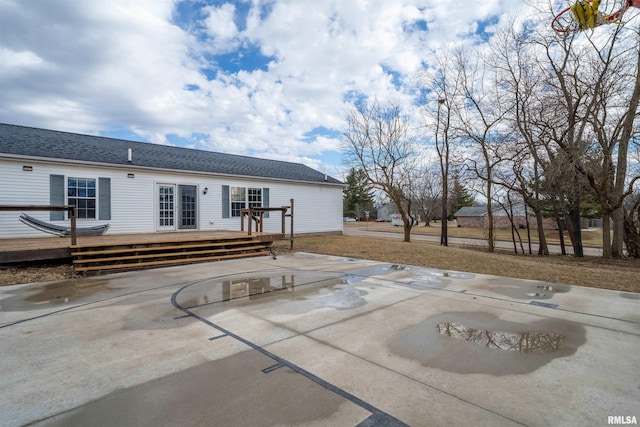 rear view of property with a patio area, a deck, and roof with shingles