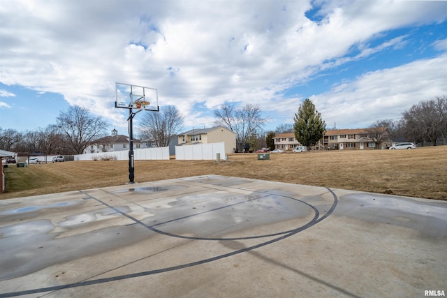 view of sport court with fence and a lawn